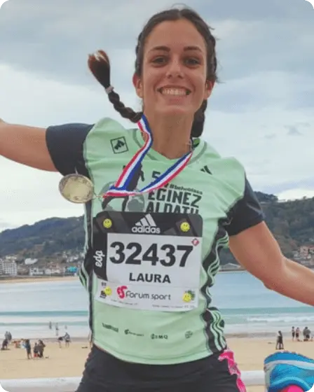 Fröhliche junge Frau nach einem Lauf, mit Medaille und sportlicher Kleidung